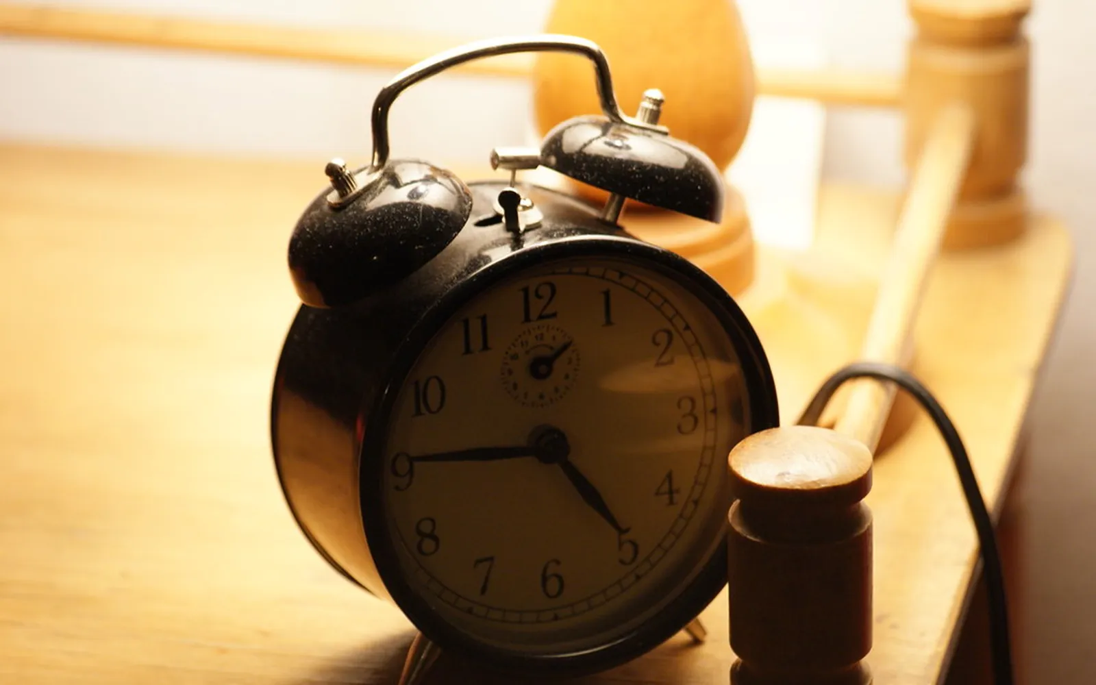An old-fashioned black alarm clock on a wooden desk